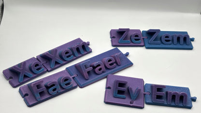 Set of purple and blue 3D-printed nameplates with various text on a white background