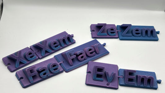 Set of purple and blue 3D-printed nameplates with various text on a white background